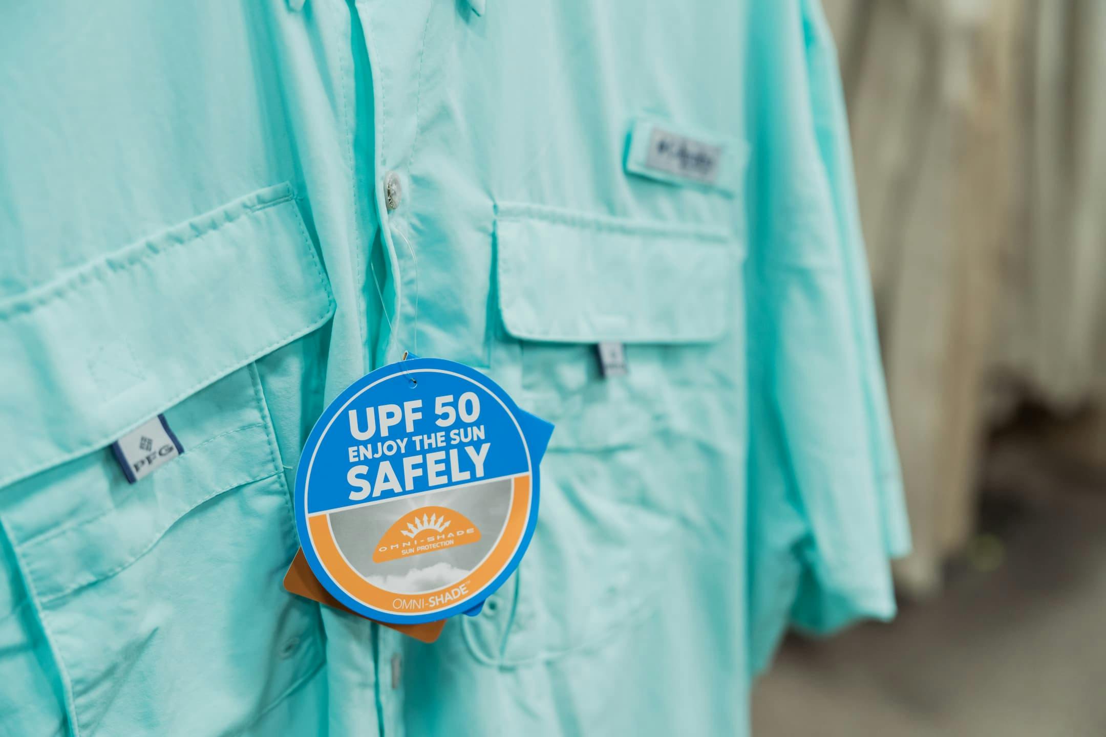 teal blue columbia pfg shirt. image focused on tag that reads "UPF 50 Enjoy the Sun Safely"